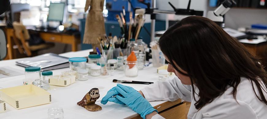 Conservator Alison Whyte prepares E972, wood bird statue for an exhibition