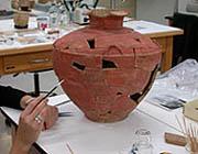 Conservator cleaning ceramic vessel